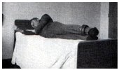 lying straight on bed with weight attached to ankle